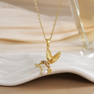 Macro detail of bird pendant with colorful crystals and pearl on gold chain