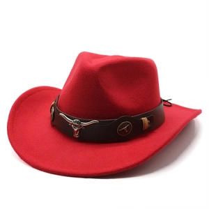 Detail of red wool felt cowboy hat featuring silver bull head emblem on brown leather band