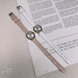 Detail of square gold quartz watches with ivory and nude leather straps for women