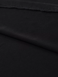 Macro view of black crepe fabric showing detailed knit texture and lockstitch sewing craft