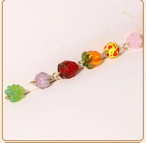 Macro detail of various colorful glass fruit charms with gold metal rings for DIY jewelry
