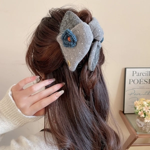 Polka dot knitted bow hair claw with blue flower on long wavy hair back view