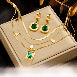 Détail du collier et boucles d'oreilles dorés avec zircon émeraude sur coffret