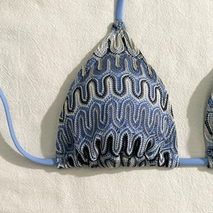 Détail d'un haut de bikini bleu avec broderie ondulée multicolore et fines bretelles