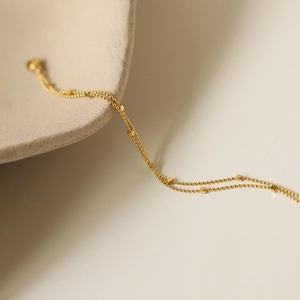 Detail of double-layer gold bead chain featuring minimalist cube charms for women