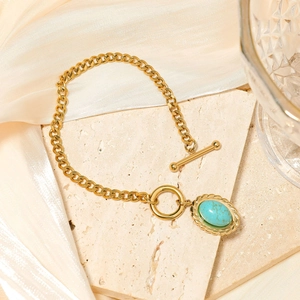 Detail of double-layer gold plated necklace with green turquoise pendant on stone texture