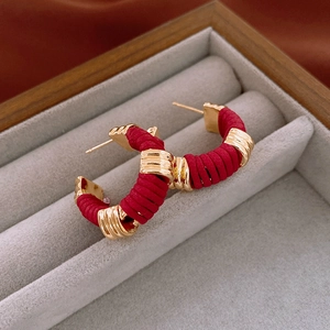 Detail of red woven leather wrapping on gold-toned C-shaped hoop earrings