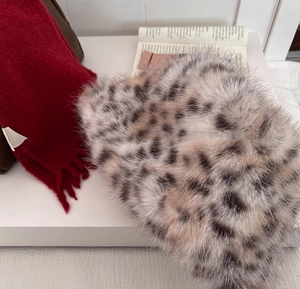 Close-up of leopard print faux fur texture and a red fringe scarf on an open book