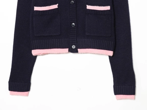 Detail of navy knit cardigan featuring pink ribbed trim on pockets and hemline