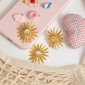Golden sunburst star earrings with white cat eye stone on minimalist white backdrop