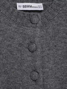 Détail de l'encolure ronde et des boutons recouverts sur le gilet en tricot gris