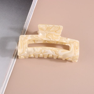Macro detail of rectangle acetate hair claw clip featuring creamy marble texture