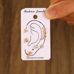 Detailed set of gold leaf and flower ear cuffs with white zircons on a display card