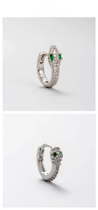 Macro view of silver snake hoop earrings featuring green zircon eyes and clear stones
