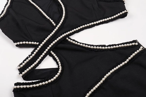 Close-up of black knit fabric with cutout design and white pearl bead accents