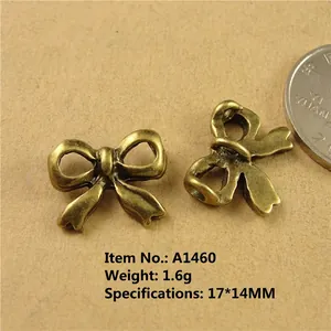 Detail of vintage bronze bow charm 17x14mm with coin for size reference and metal specs