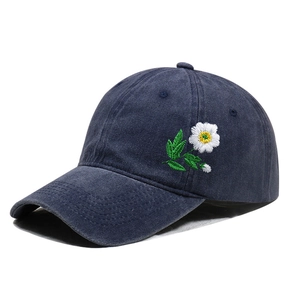 Detail of white daisy floral embroidery on vintage washed navy denim baseball cap