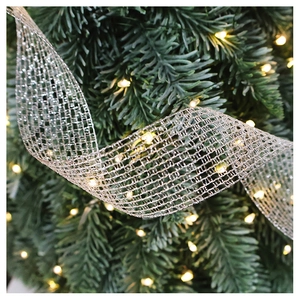 Macro detail of silver mesh ribbon with warm LED lights wrapped around Christmas tree