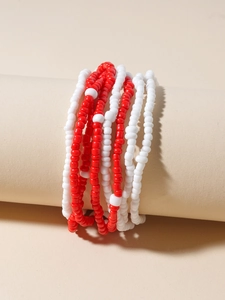 Detail of red and white handmade seed bead waist chains on a minimalist beige pedestal
