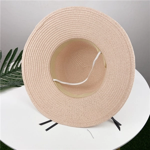 Detail of hand-woven beige straw hat featuring internal elastic strap and brim texture