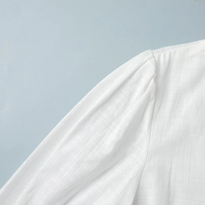 Detail of pure white cotton fabric showing pleated puff sleeve seams and linen texture