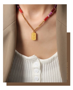 Detail of a gold square pendant necklace with Chinese characters and colorful beads