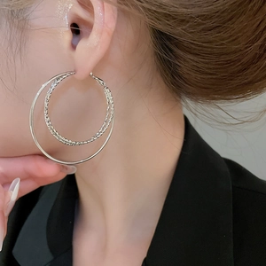 Close-up of double layered silver hoop earrings with textured inner ring on model