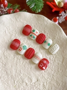 Macro detail of Christmas themed press-on nails with elk, snowflake and sweater texture