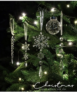 Close-up of acrylic snowflakes and icicles hanging on a lit Christmas tree