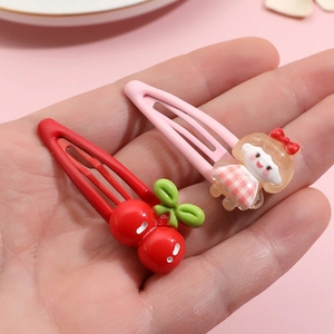 Close-up of cute fruit and girl character hair clips held in hand for size scale