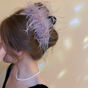 Detail of purple feather hair claw clip with hanging silver rhinestone tassels for styling