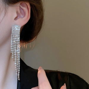 Gros plan de boucles d'oreilles à pompons argentés avec strass brillants sur un mannequin