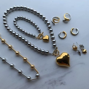 Flat lay of polished gold and silver heart jewelry set on marble background