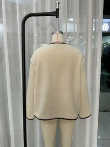 Dettaglio della giacca in pile bianco sporco con bordi rifiniti in marrone scuro