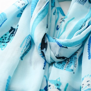Close-up of lightweight blue fabric texture with cute white cat pattern on silk scarf