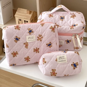 Detailed set of three pink striped quilted bear makeup bags on a wooden shelf