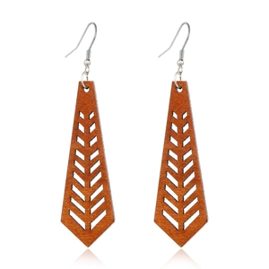 Macro view of brown wooden earrings with geometric cutout and herringbone patterns