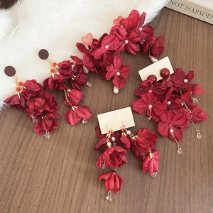 Makroansicht der roten Vintage-Blumenohrringe mit Perlenquasten auf dunklem Holz