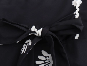 Detail eines geblümten Kleides mit Knotenschleife und weißem Wellenspitzenbesatz
