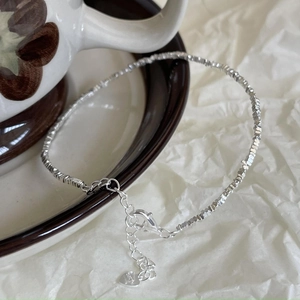 Macro shot of S925 sterling silver square bead bracelet with heart charm on a ceramic saucer
