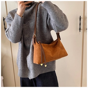 Brown suede crossbody bag featuring leather tassels and a sleek gold hardware detail