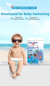 Toddler wearing Uber Bear disposable swimming diaper on a beach with product packaging