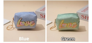 Detail of glitter fabric coin purses with LOVE sequin embroidery in blue and green
