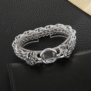 Detailed view of silver double lion head bracelet with braided metal chain on leather