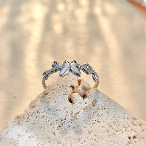 Detailed view of a silver butterfly ring with crystal accents on a textured stone