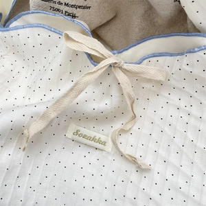 Detail of white polka dot canvas bag showing knit texture, blue edge, and drawstring tie