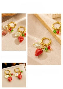 Detailed macro view of gold-plated strawberry earrings with butterfly charms