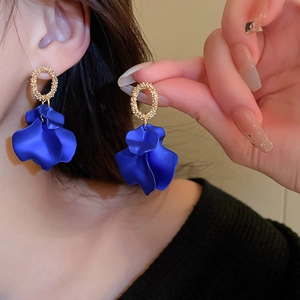 Close-up of elegant gold textured stud earrings with layered matte dark blue flower petals