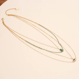 Detail of layered gold necklace featuring turquoise beads and evil eye pendant charm