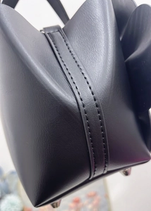 Detail of black pebbled leather tote showing fine stitching and silver protective metal feet